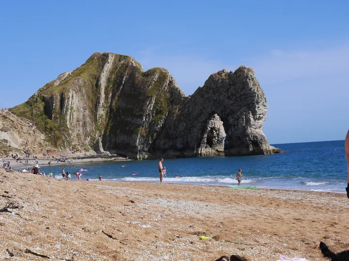 People enjoying a beach beneath a sea arch